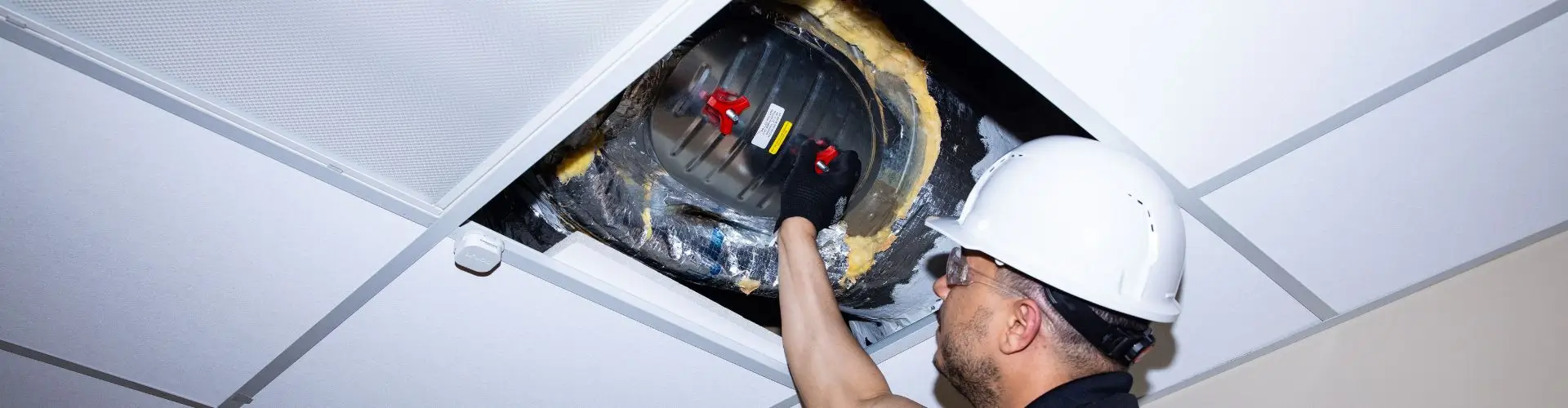 A Health Choice Enterprises employee conducts an above ceiling inspection.